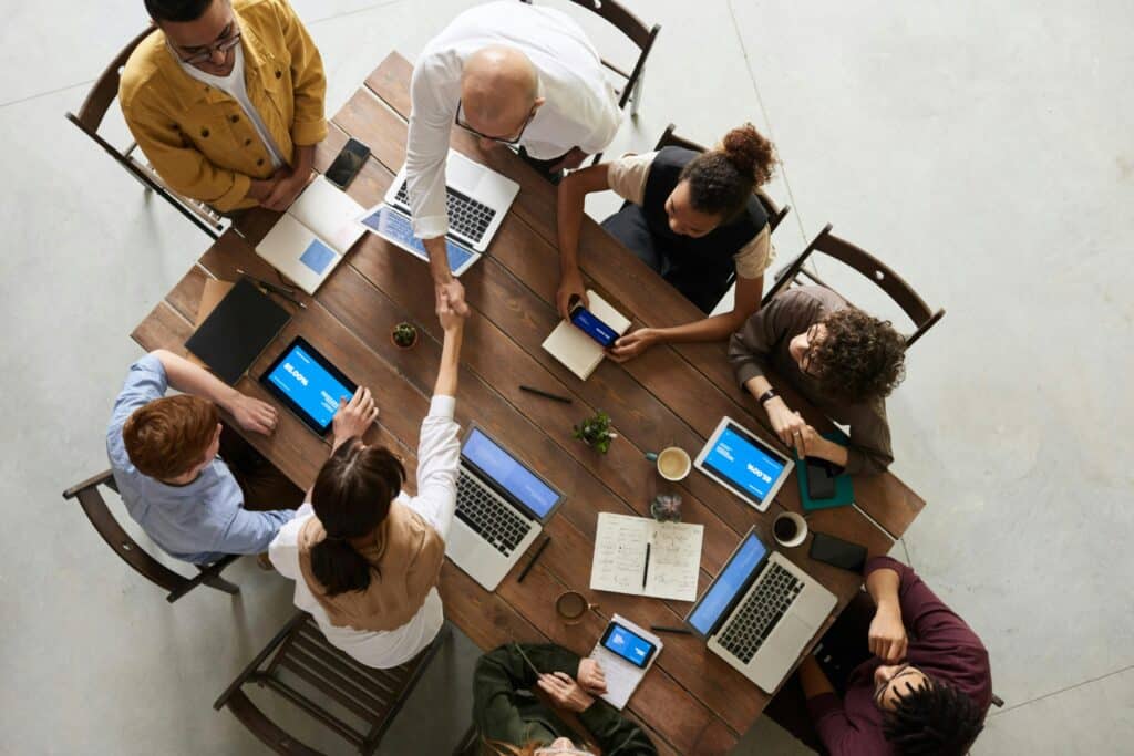 Business team meeting around table collaborating on laptops and tablets